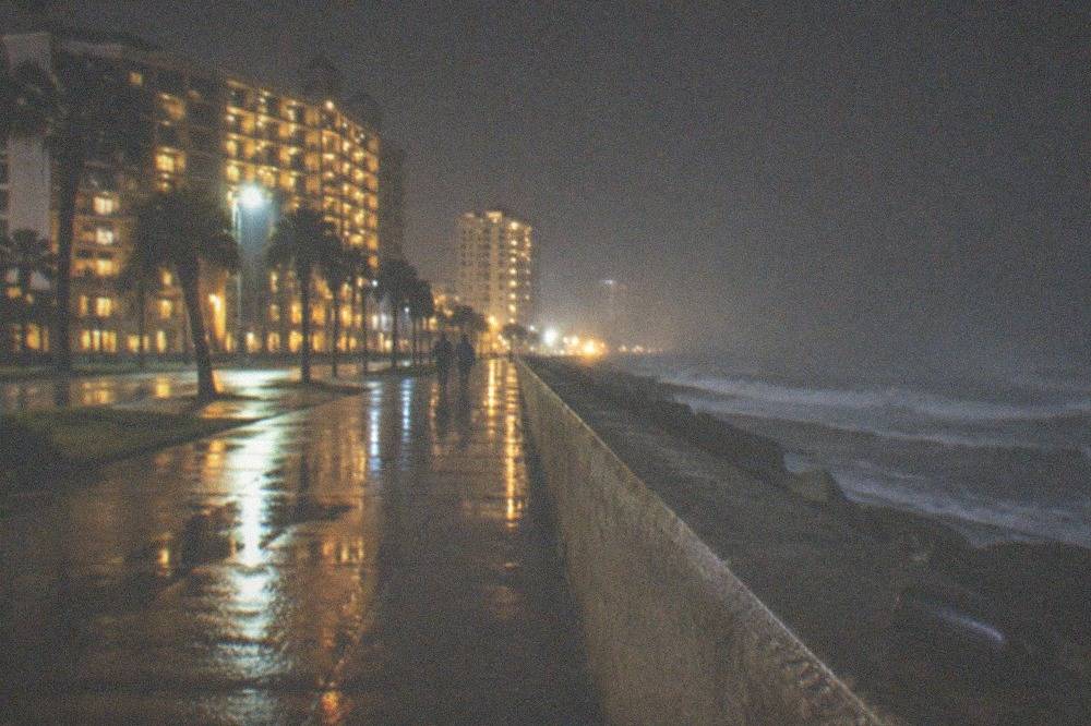 Seawall boulevard at night with hotel lights reflecting on the sidewalk