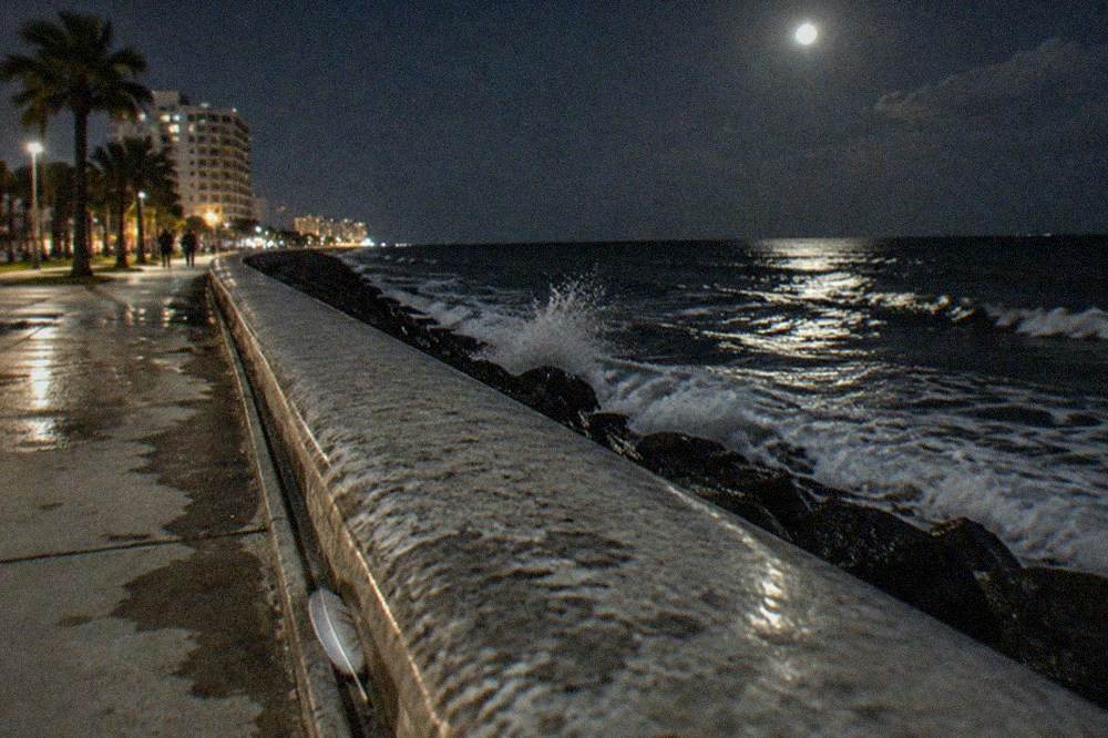 A concrete seawall curving along a dark Gulf horizon at twilight