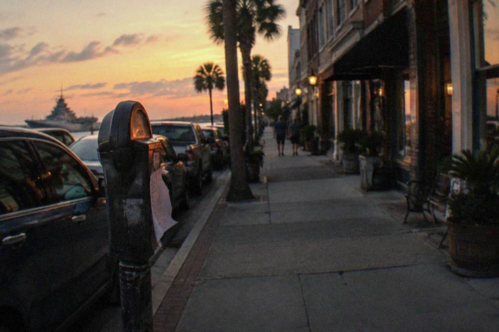 A quiet downtown street corner at dusk with parked cars along the curb