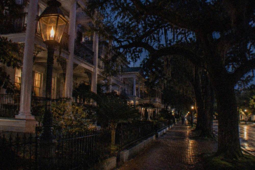 A gas-lit street corner in the East End historic district with Victorian mansions in the background