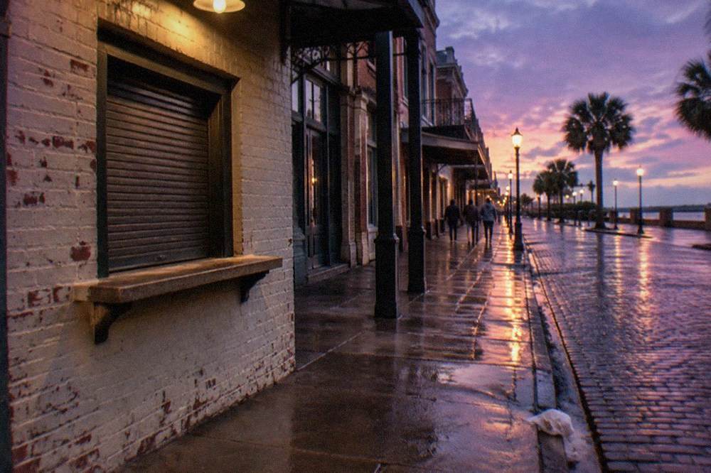 A ticket window and sidewalk outside a historic brick building on The Strand at dusk