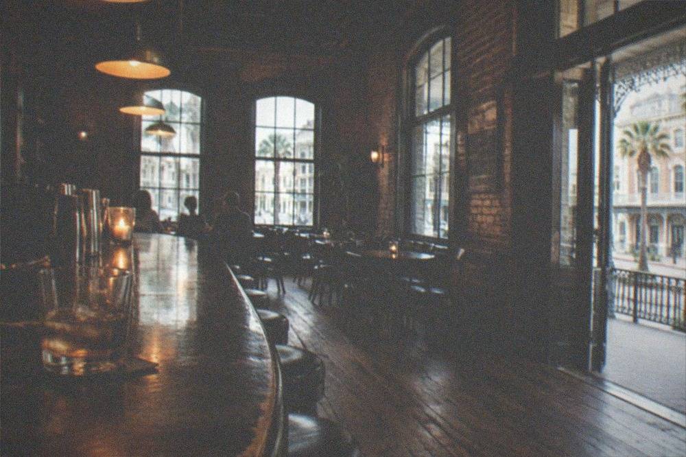 A dimly lit historic bar interior with wooden floors and hanging lights
