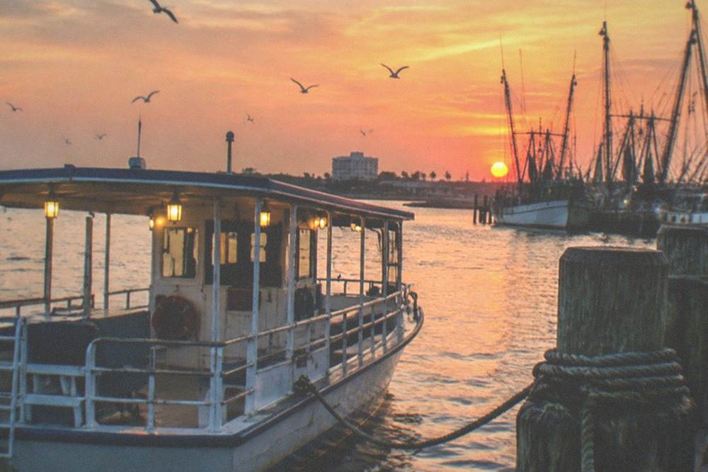 A tour boat at a dock on the Galveston harbor front under evening sky