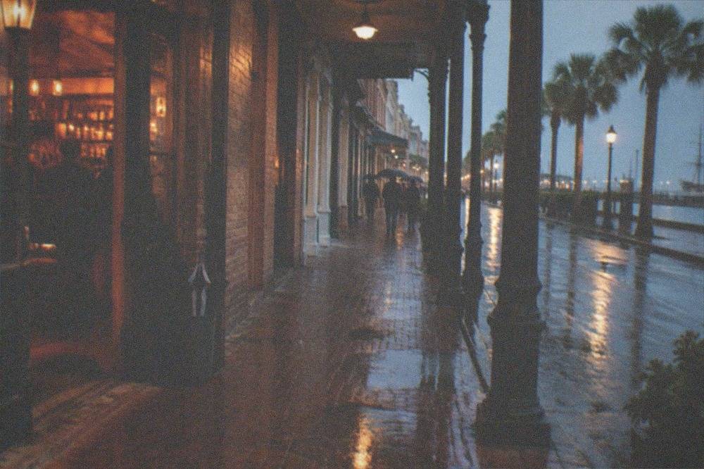 Strand bar exterior at night with warm light spilling onto the brick sidewalk