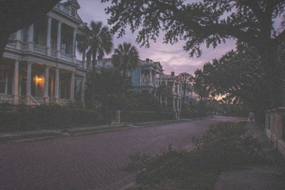 A wide brick avenue lined with historic mansions under evening sky