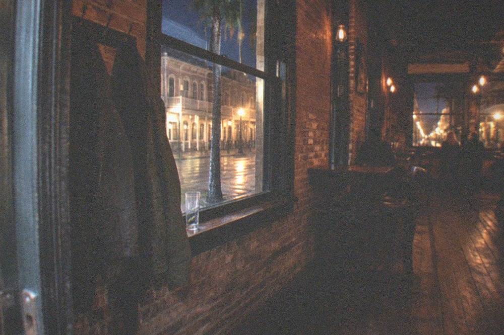 A dimly lit historic bar interior with brick walls and hanging Edison bulbs