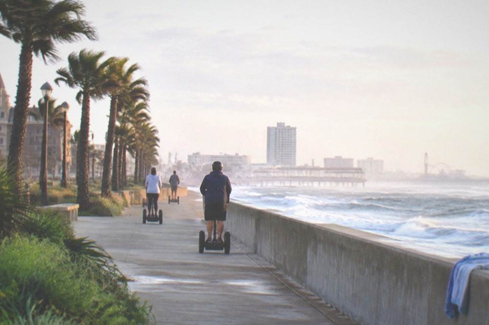 Segway riders rolling along a seawall path in morning light