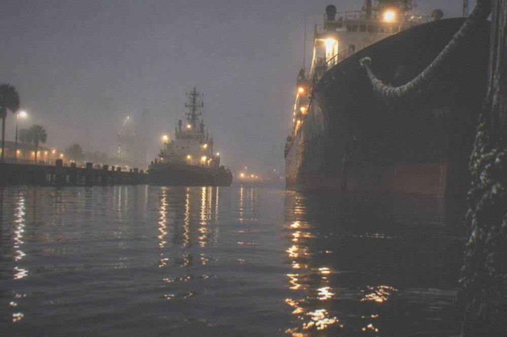 Calm Galveston harbor water at night with reflected lights from docked ships