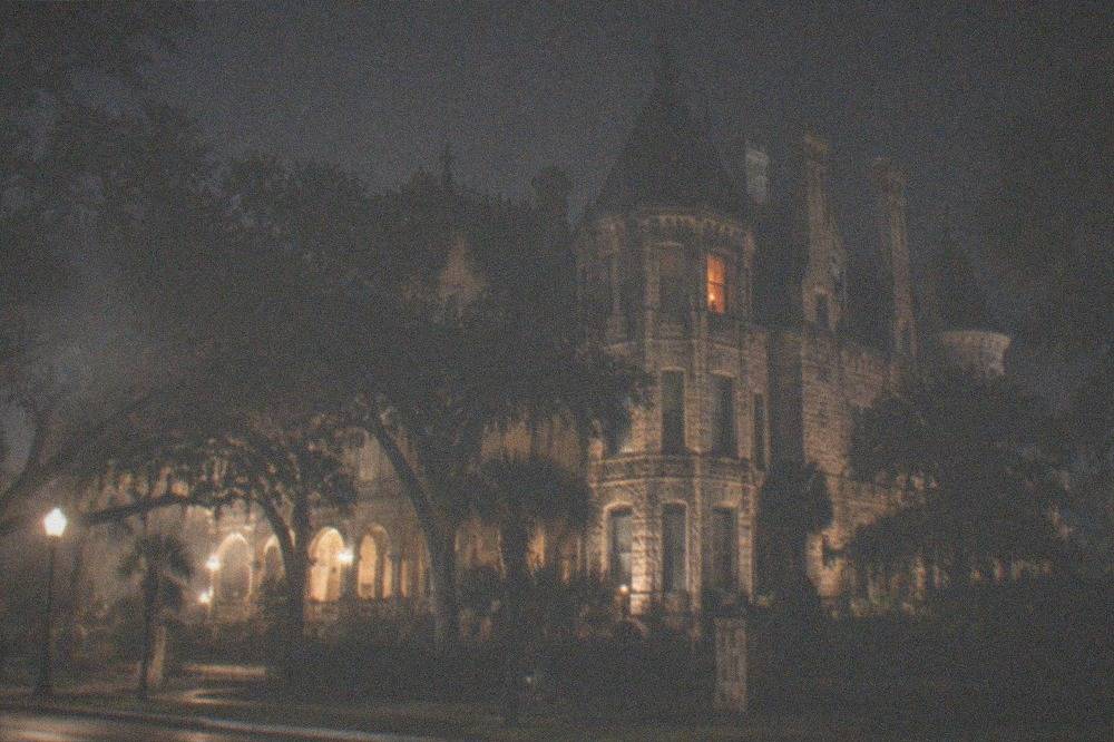 Historic mansion exterior lit against a night sky
