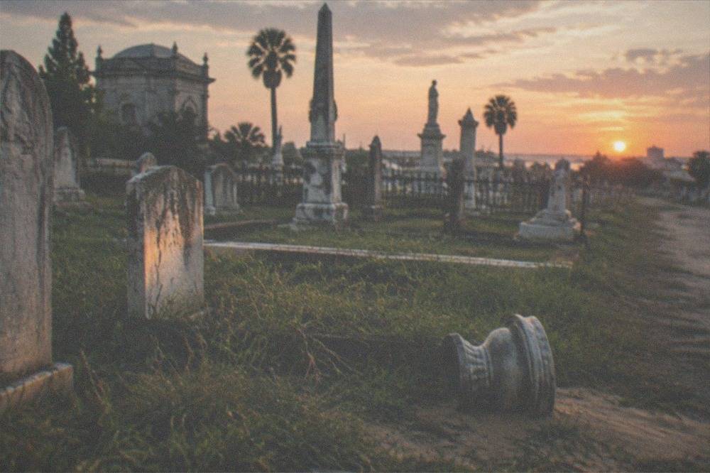 Rows of old headstones with weathered inscriptions in a Galveston cemetery at dusk