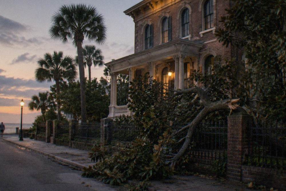 A three-story Italianate brick mansion with arched windows and a wide porch at dusk.