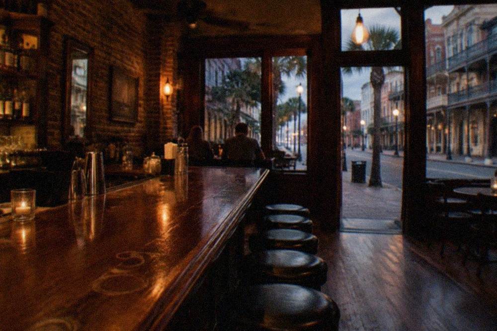 A dimly lit historic bar interior with brick walls and a long wooden counter