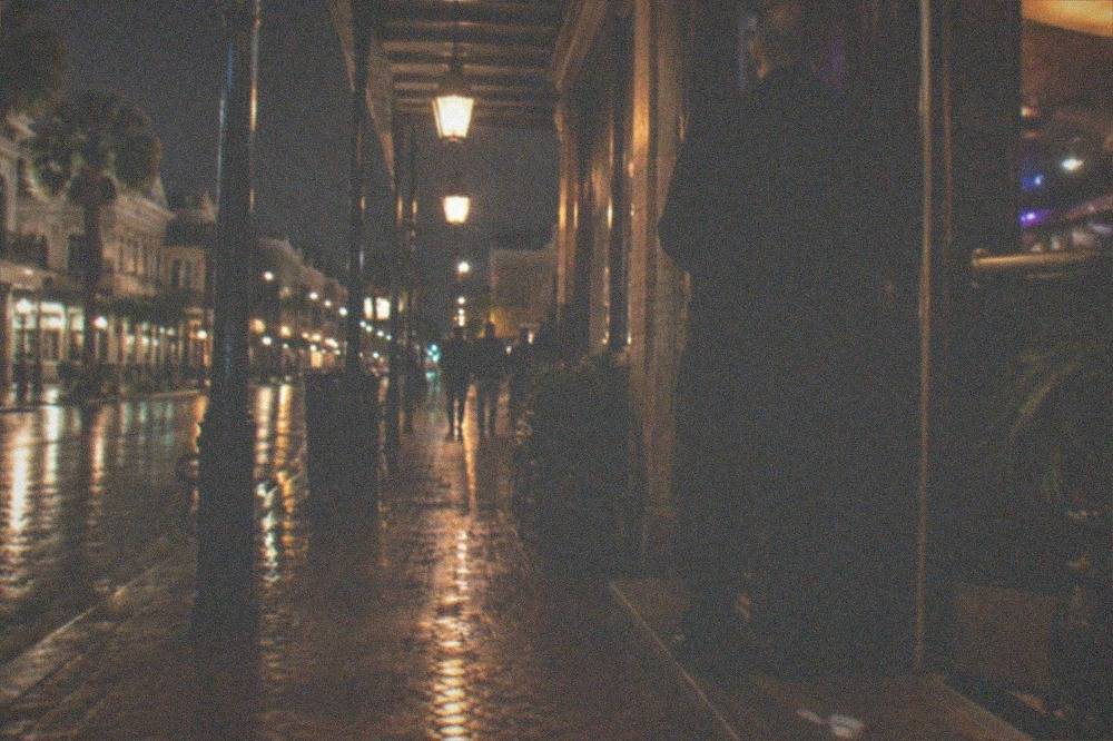 A bouncer checking identification at the door of a lit bar entrance at night