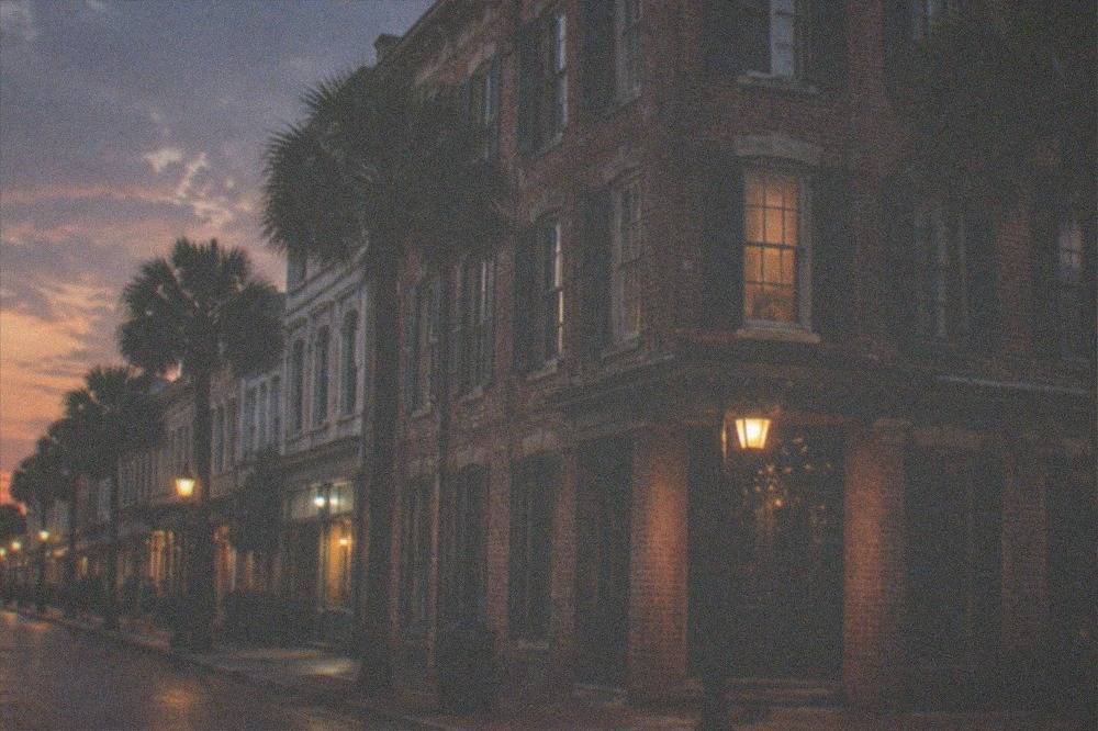 An old brick hotel facade with tall windows and a corner entrance at twilight