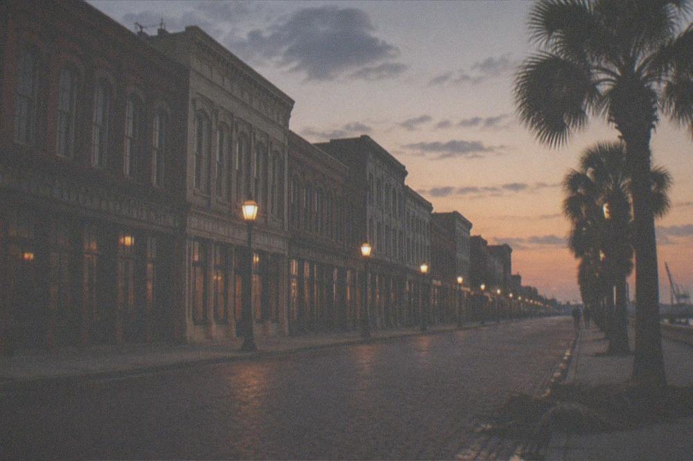 Street lamps and parked cars along a historic commercial block after sunset