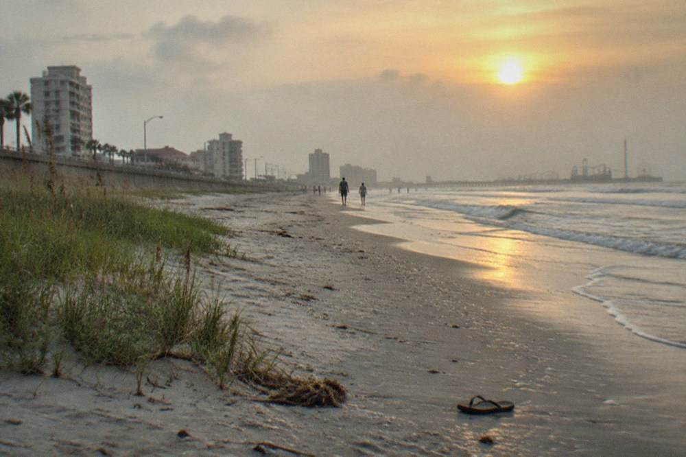 Wide beach along the Galveston seawall with the boulevard on one side and the Gulf on the other