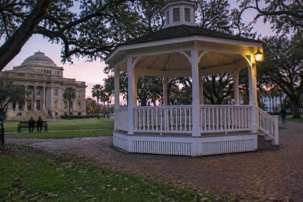 An open-air wooden gazebo on a downtown street corner at dusk