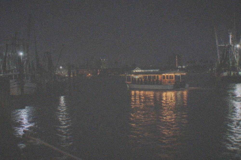 A lit ferry and harbor buildings seen across dark water at night